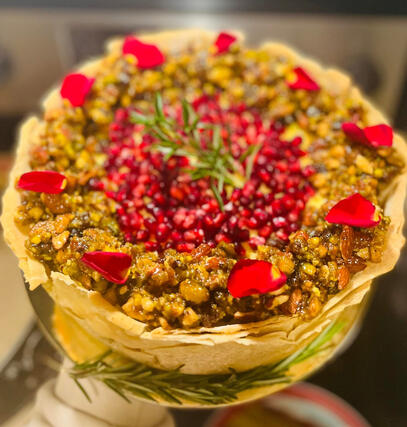 Baklava Cheesecake- Homemade Phyllo Dough, A Layer Of Crushed Almond, Pistachios &amp; Walnuts w/ Butter, Orange Flavored Cheesecake, Honey, Rose Water &amp; Walnut Syrup, Topped w/ Pomegranate Seeds &amp; Rose Petals